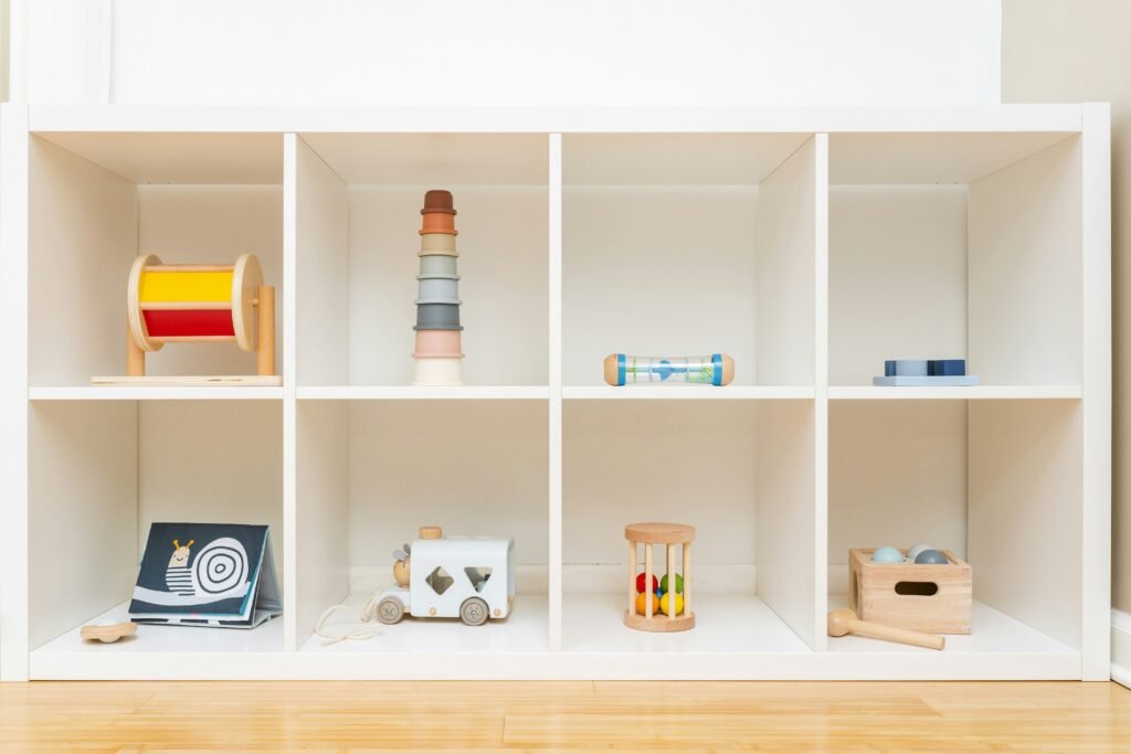 Low shelf with eight cubbies containing a variety of simple, wooden toys.